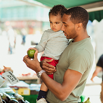 Man holding baby with apple in hand